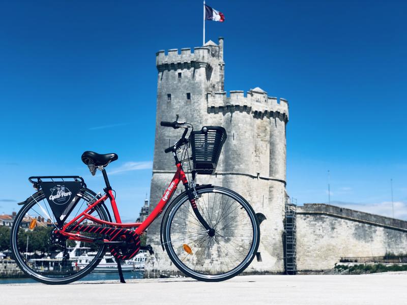Un vélo de ville rouge, face à la tour Saint-Nicolas.