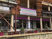 Devanture du restaurant avec terrasse extérieure avec tables et chaises. Panneau avec inscription : "Pourquoi pas ? Crêperie Pizza" "Spécialités montagnardes"