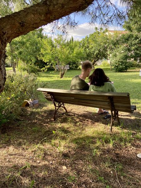 Un couple assis sur un banc, dans un espace vert du campîng.