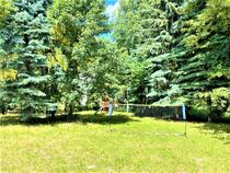 Jardin ensoleillé avec aire de jeux et filet de volley-ball