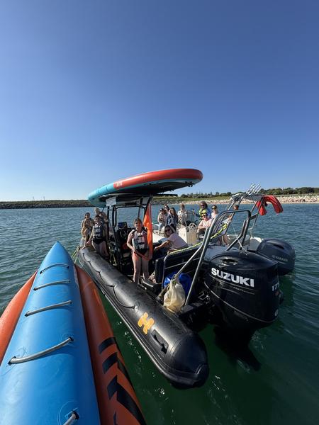 Un groupe de personnes sur  le zodiac, une bouée tractée banane sur le côté, un paddle géant sur le toit.