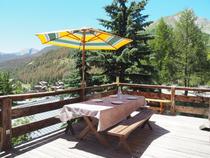 Table d'extérieur sur terrasse en bois, vue sur les montagnes en été