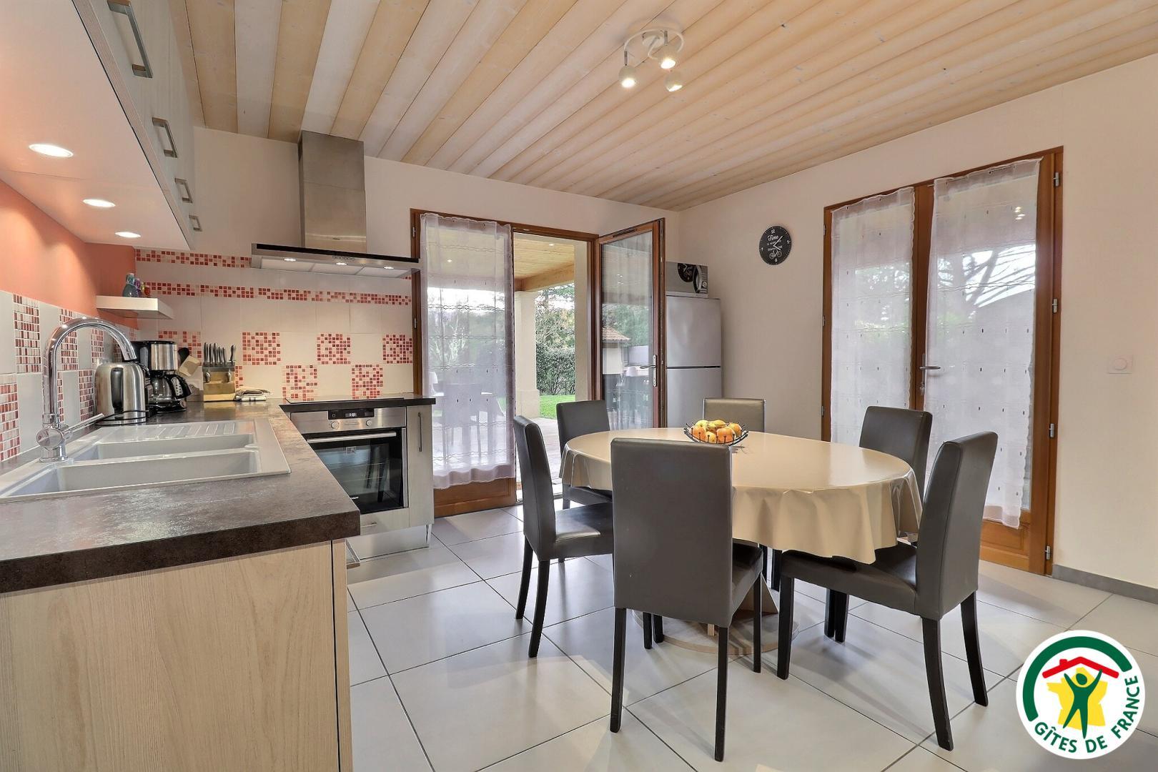 Coin cuisine équipée, petit espace repas et accès terrasse