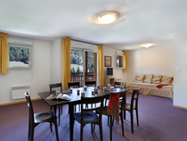 Salon d'appartement avec table à manger, canapé, TV, ameublement bois, fenêtre