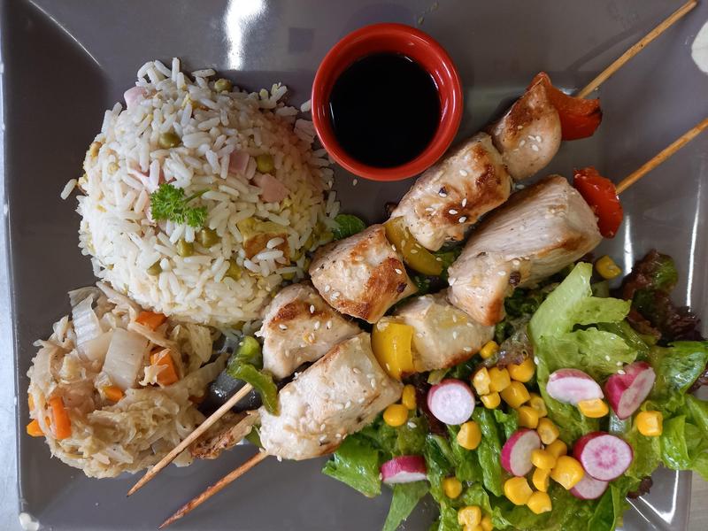 plat copieux composé de riz brochette sauce soja radis salade composé mais