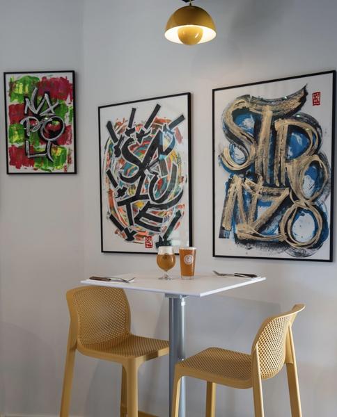Une table haute 2 personnes devant des tableaux, à l'intérieur du restaurant