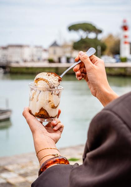 Une personne tenznt une glace, face au port.
