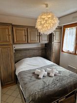 Chambre double avec meuble de rangement encadrant le lit, linge de toilettes et fenêtre