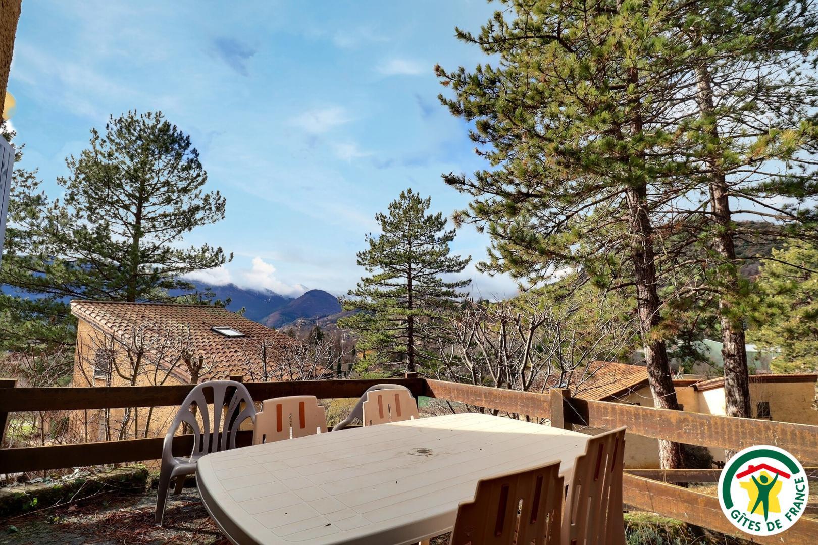 Terrasse privative avec salon de jardin, vue sur les maisons et la montagne