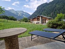 Terrasse en été avec vue sur les montagnes, résidence voisine, mobilier de jardin