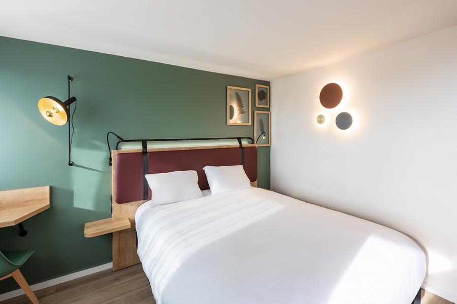 Une chambre avec lit double, le mur est vert.