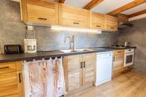 Cuisine moderne et lumineuse avec plaques au gaz, ameublement bois, parquet au sol