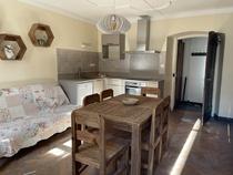 Séjour d'appartement lumineux avec table à manger, canapé, coin cuisine avec four, plaques électriques, lave-vaisselle