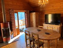 Séjour de chalet en bois avec table à manger, TV, poêle à bois, ameublement bois, fenêtre