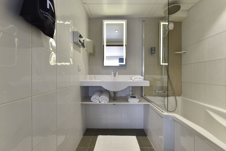 Salle de bain avec baignoire avec serviettes, sèche-cheveux