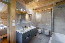 Salle de bains avec double vasque et son meuble, double miroir, deux toilettes et baignoire