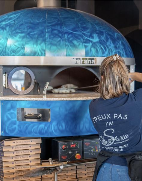 Employée devant le four à pizza