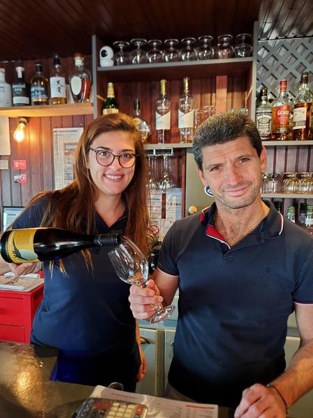 Une jeune femme servant un verre de vin au gérant, Gérald.