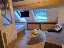 Coin chambre à coucher du studio, canapé, lit double, fenêtres velux, TV, espaces de rangement