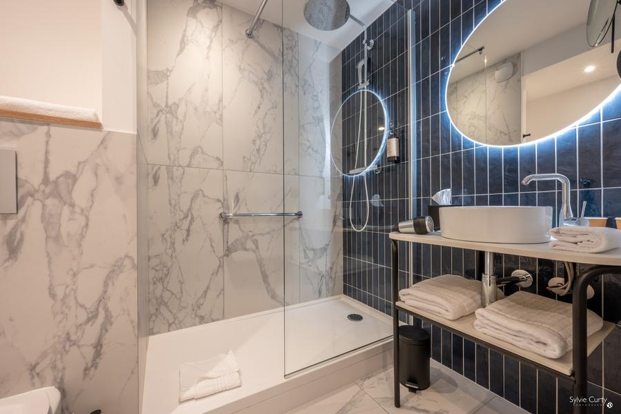 Une salle d'eau avec douche, évier, serviettes, miroir.