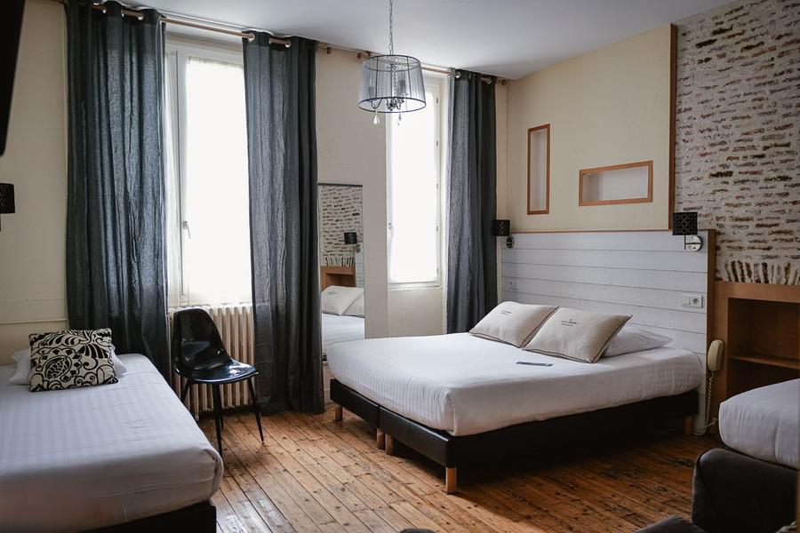 Chambre avec lit double, lit simple, parquet, miroir, rideaux.