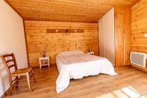 Chambre à coucher lumineuse avec lit double, ameublement bois, parquet au sol, fenêtre