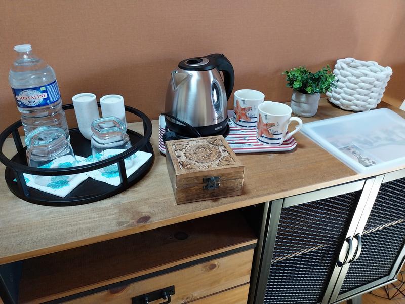 Un plateau d'accueil avec une bouilloire, des tasses, une boite à thé, une bouteille d'eau et des verres.
