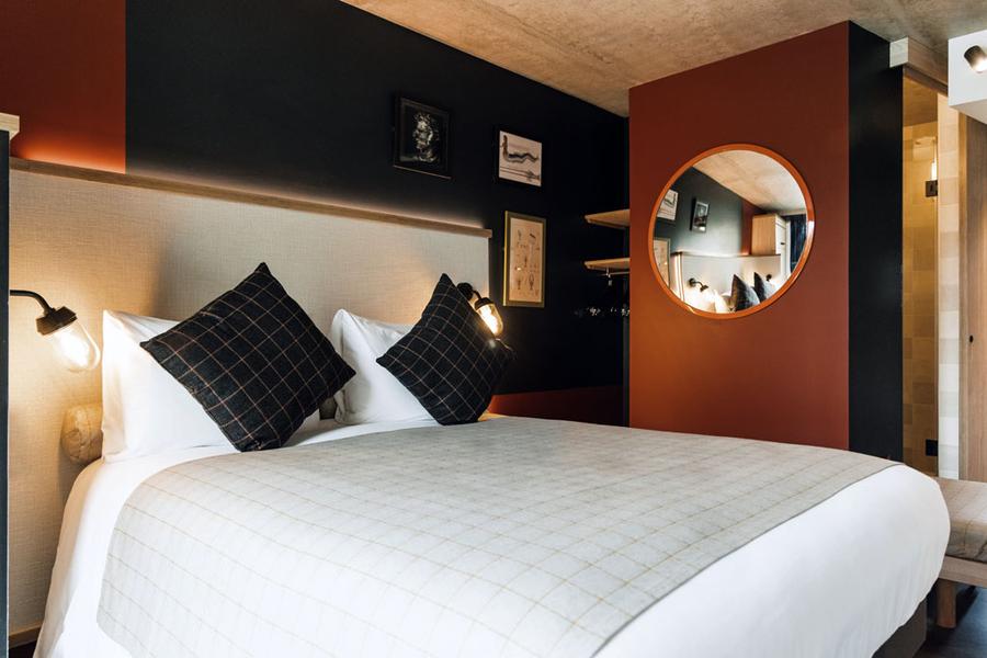Une chambre avec un lit double et un miroir au mur.