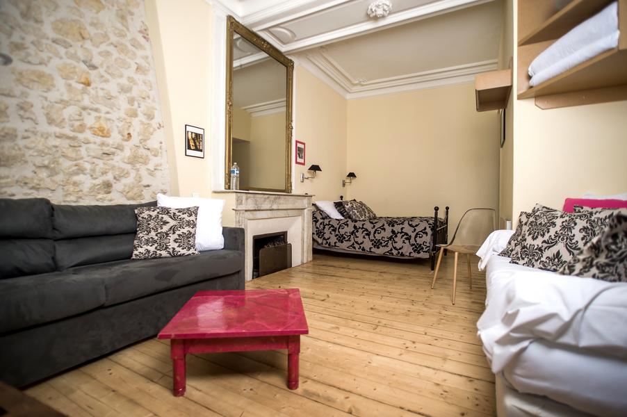 Une chambre avec un lit, une cheminée avec un grand miroir au dessus, un canapé.