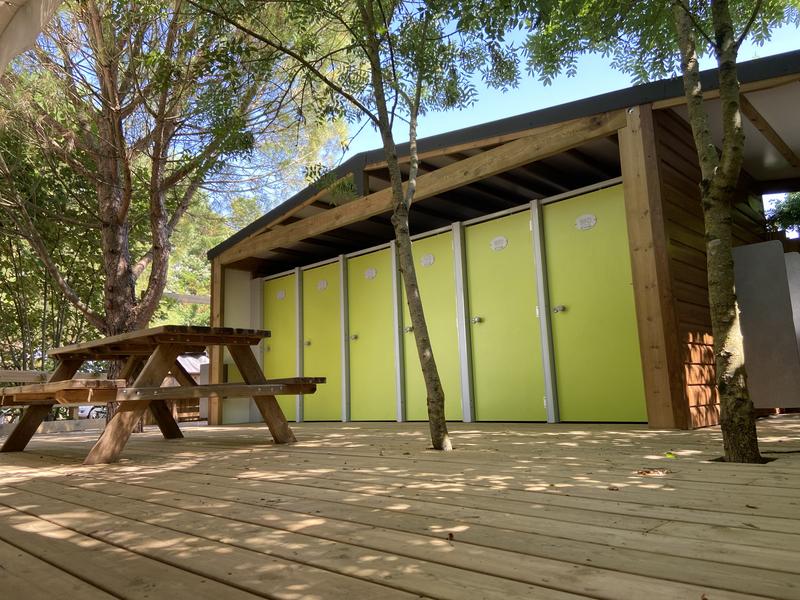 Le bloc sanitaire vert, avec une table de picnic installée devant.