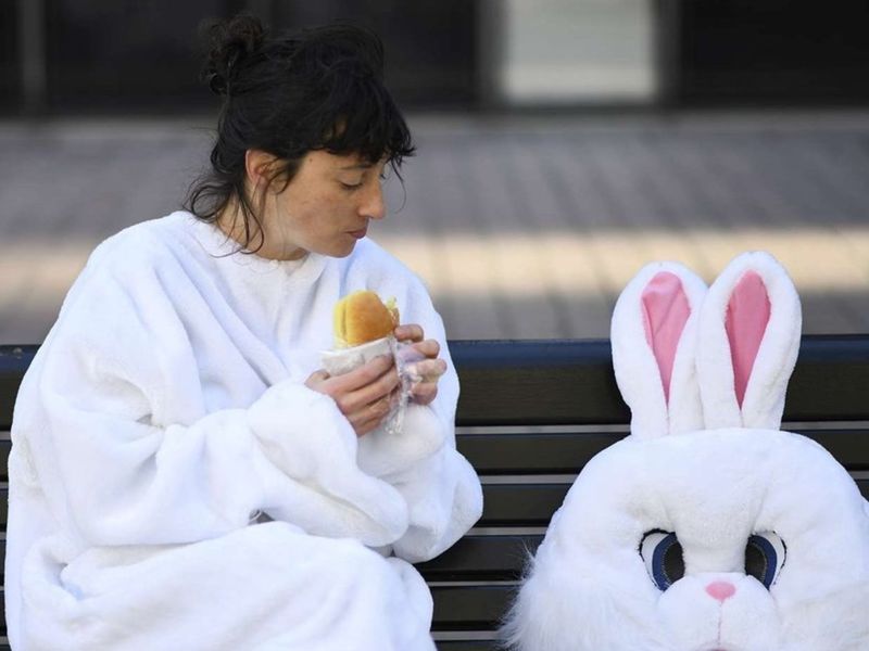 Dame déguisée en lapin mangeant sur un banc
