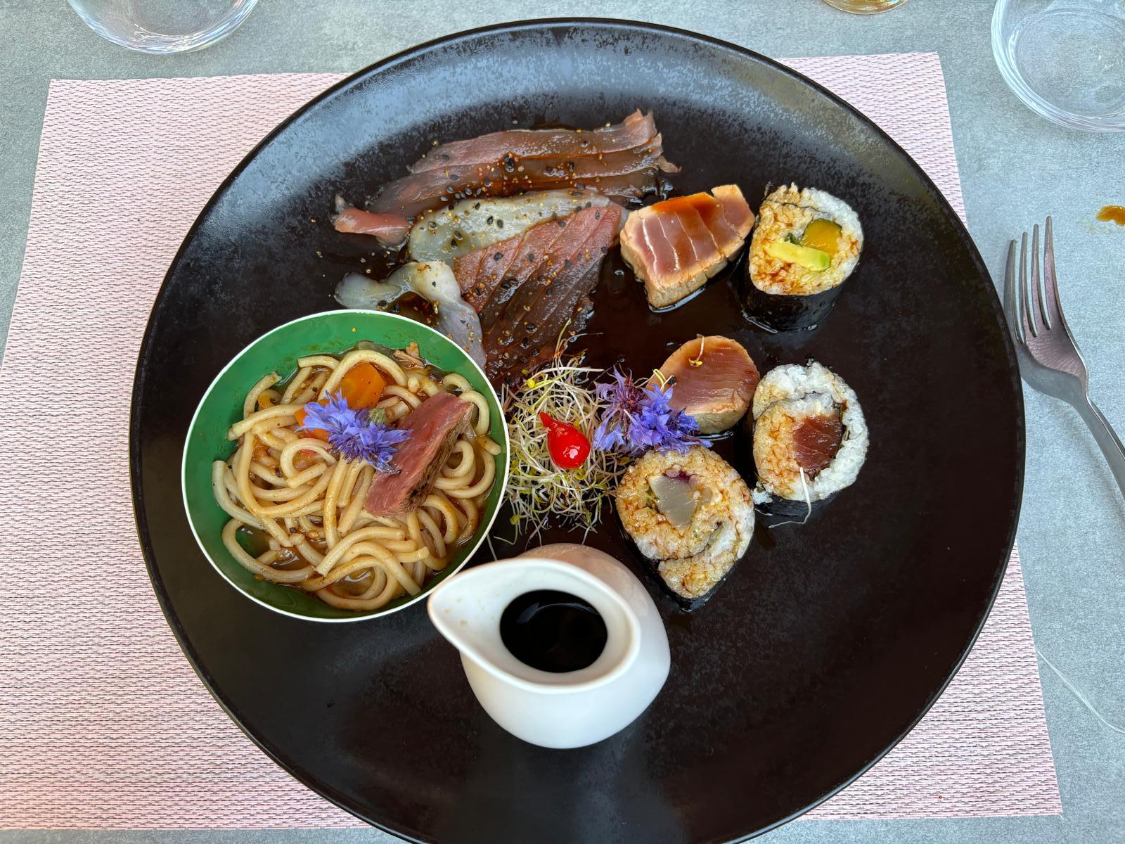 Assortiment d'inspiration asiatique associant thon mariné, makis, nouilles sautées.