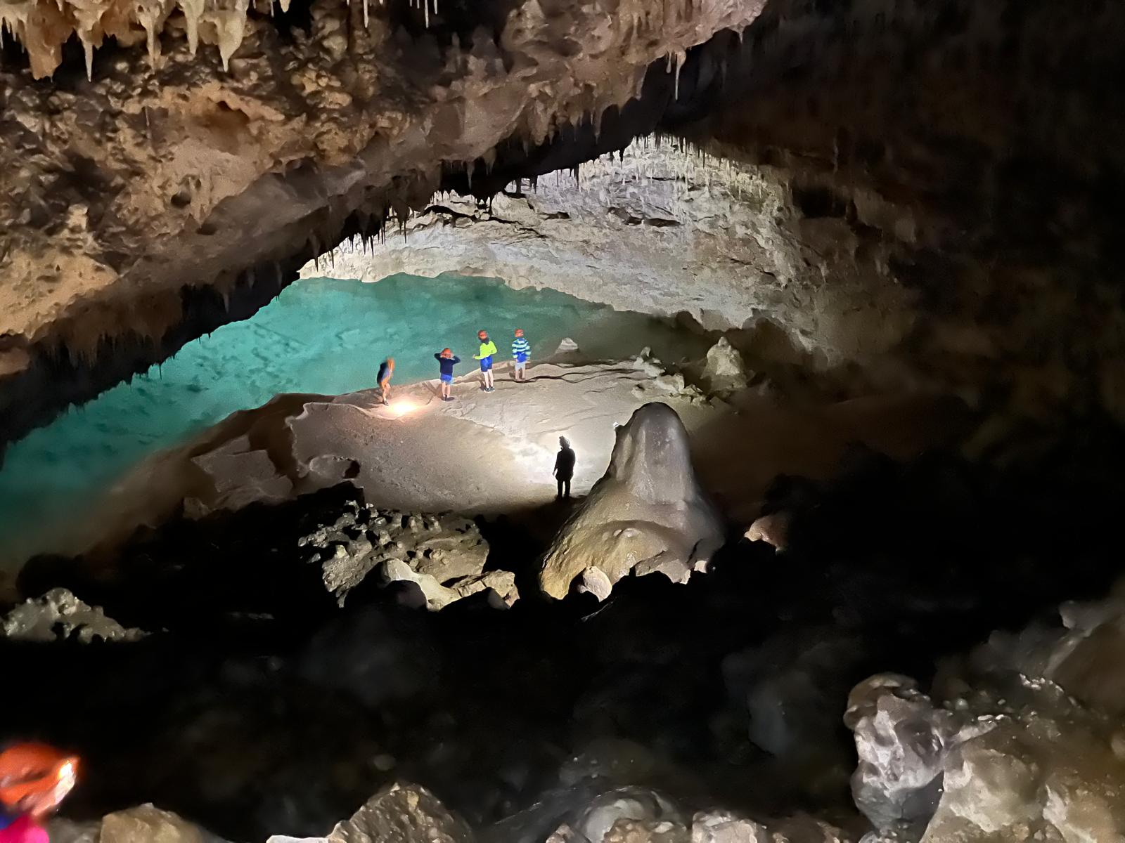 5 personnes au bord d'un lac souterrain.