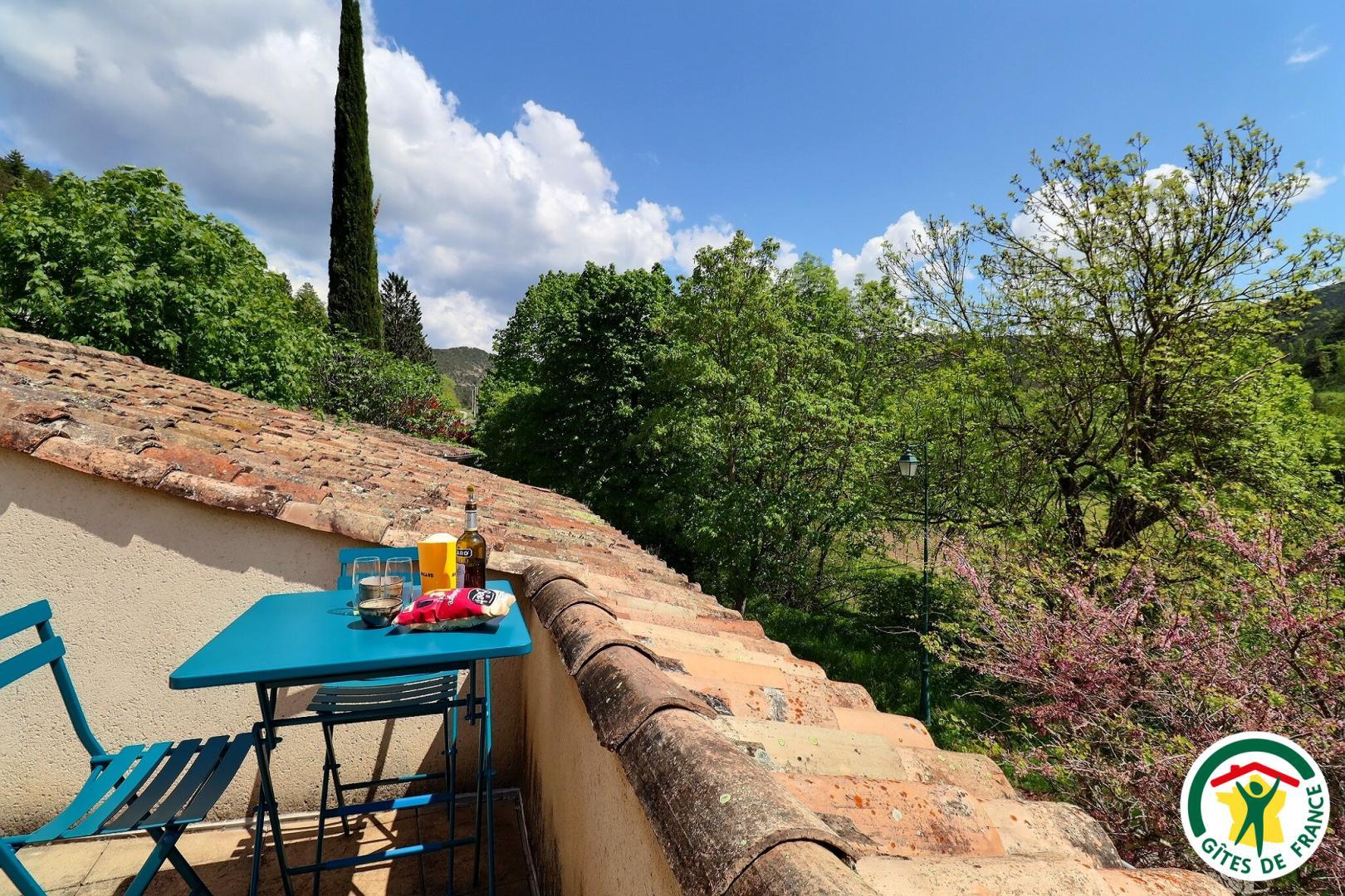 Toit-terrasse avec bains de soleil, table et chaises hautes, store-banne. Vue campagne et hameau