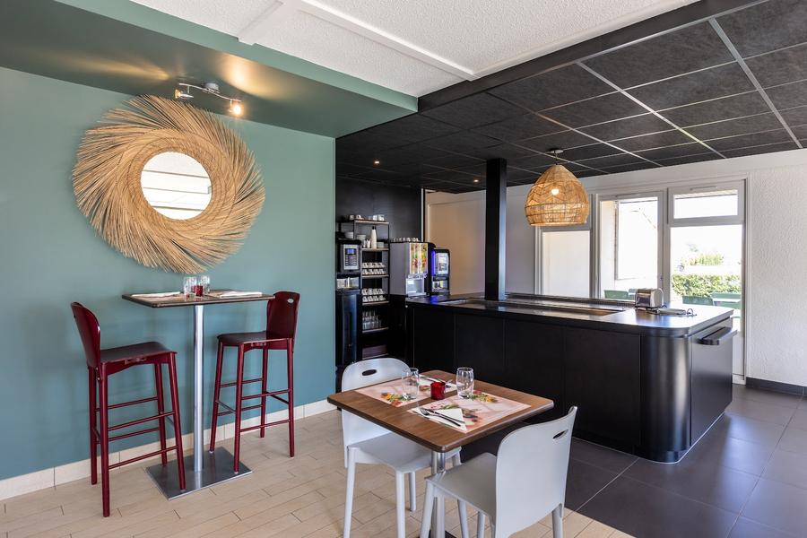 la salle de restaurant et l'accueil de l'hôtel, avec un table basse et une table haute.