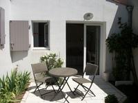 Une terrasse avec une petite table ronde et deux chaises métalliques.