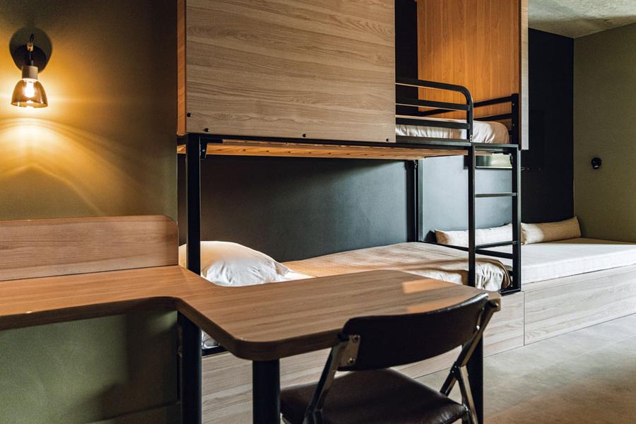 Un bureau et sa chaise, deux lits simples superposés, et une banquette.