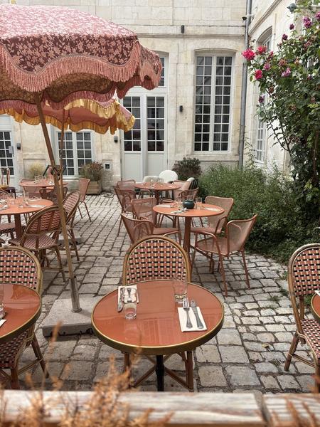 la terrasse dans la cour avec des tables et des parasols.