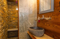 Salle de bains avec vasque en pierre, sous-vasque en bois, murs en pierre de la douche