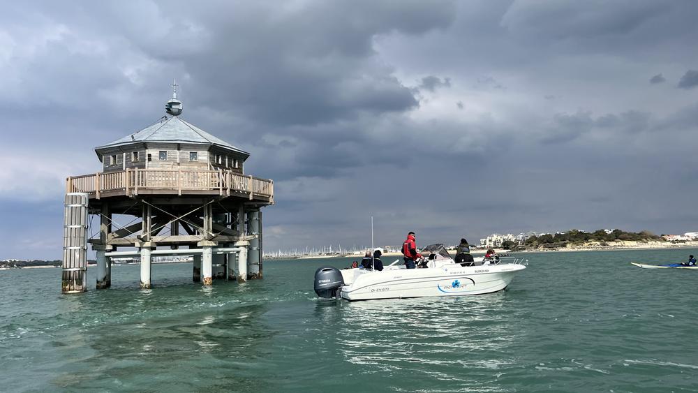 Un bateau à moteur à côté du phare du Bout du Monde.