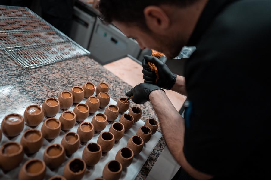 Un chocolatier remplissant des oeufs en chocolat.