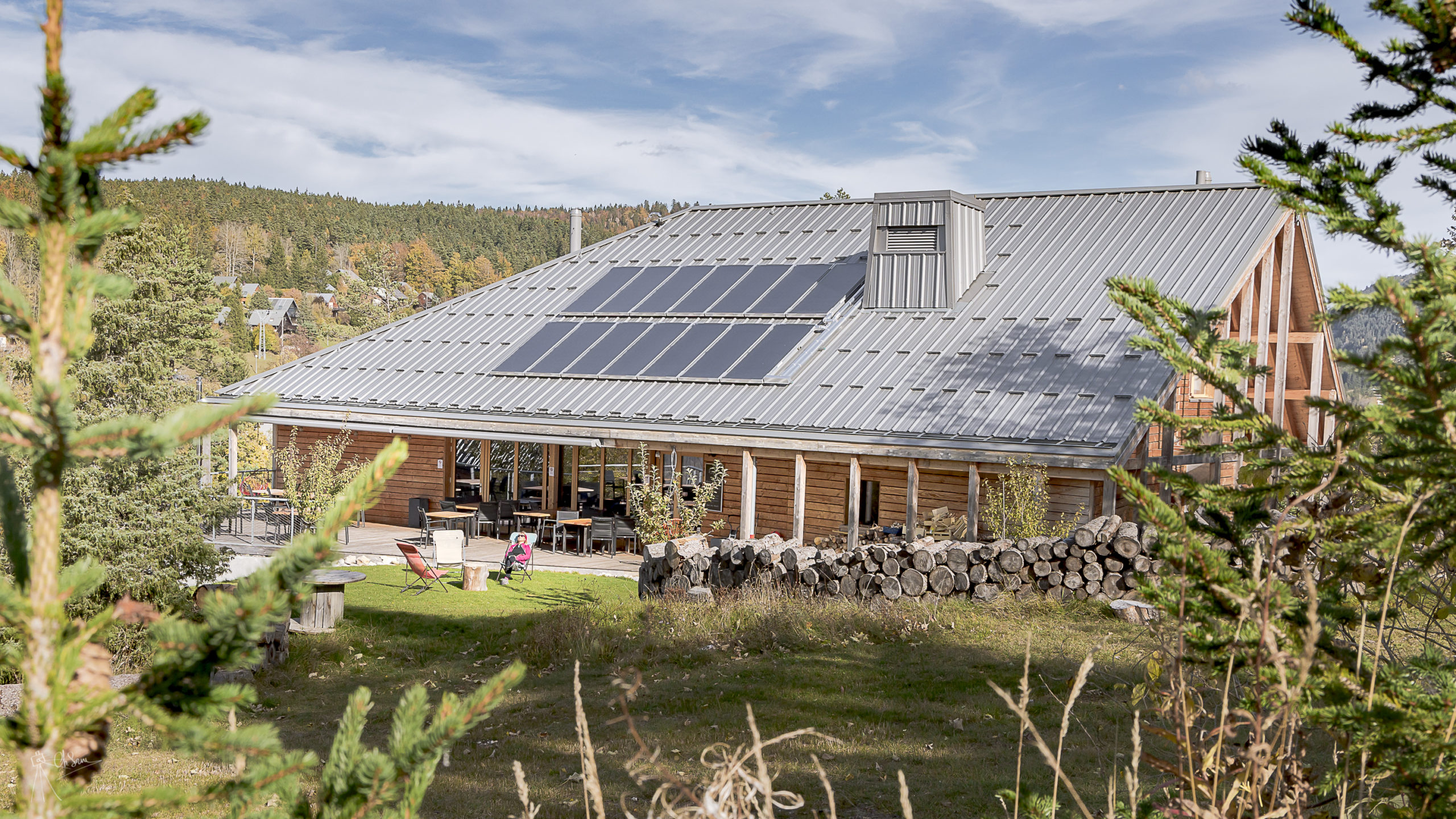 Bâtiment en bois avec des arbres vert et orangés, à l'automne