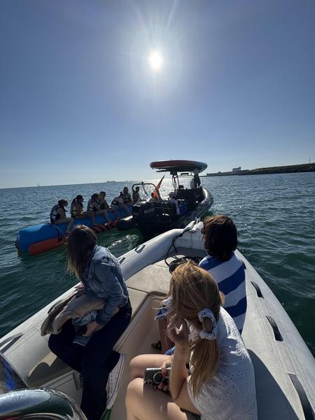 Un bateau à moteur, un zodiac et une banane tractée avec des gens dessus.