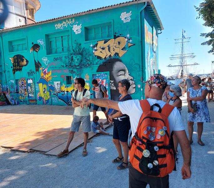 Le guide et un groupe devant une fresque bleue.