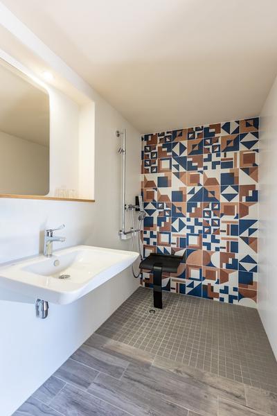 une salle d'eau pour les personnes à mobilité réduite, sans démarcation entre la douche et le reste de la pièce.