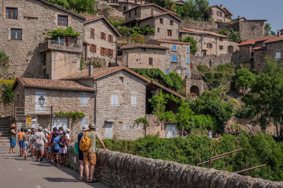 personnes sur le pont du chastelas et quartier médiéval à Jaujac (Ardèche)