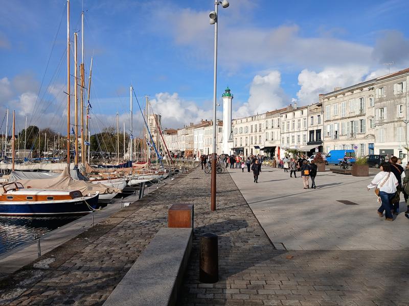 Le vieux port à gauche, la rue piétonne à droite avec des passants.