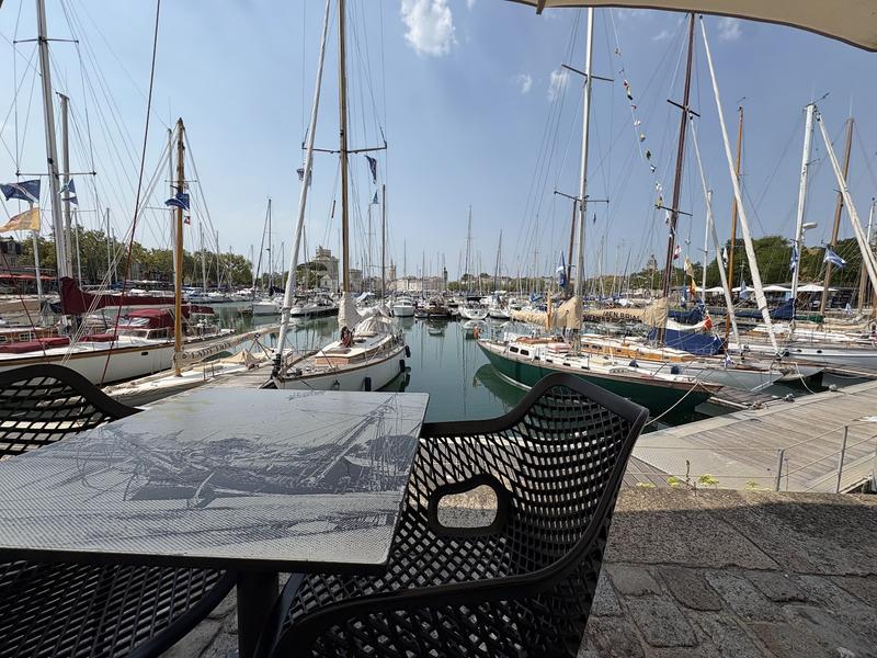 Une table vide et ses deux chaises sur le port.